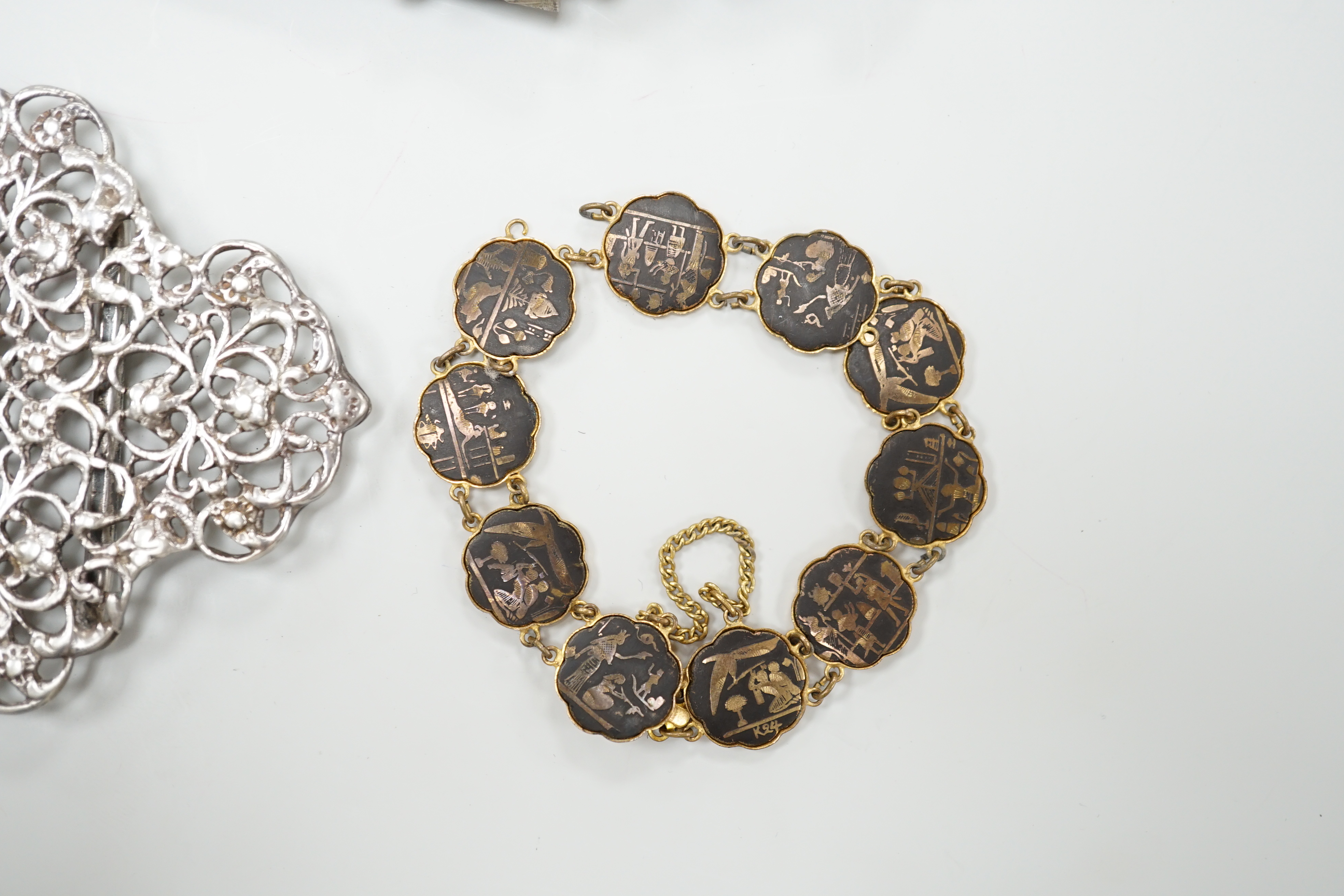 A late Victorian silver and hardstone Scottish dirk brooch, 11.75cm, an Edwardian silver vesta case, a white metal belt buckle, a hardstone pendant, a gilt metal Egyptian theme bracelet and a miniature steel sword